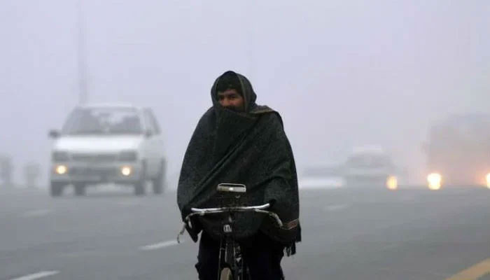A man wrapped in a shawl rides his bicycle in Islamabad. — AFP/File
