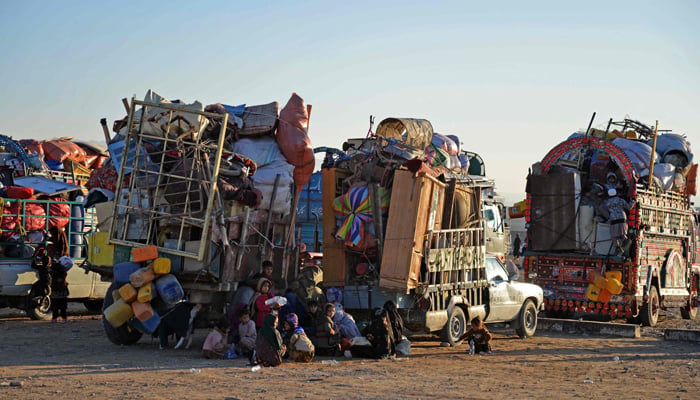 Afghan refugees along with their belongings sit beside the trucks at a registration centre, upon their arrival from Pakistan in Takhta Pul district of Kandahar province on December 18, 2023. — AFP