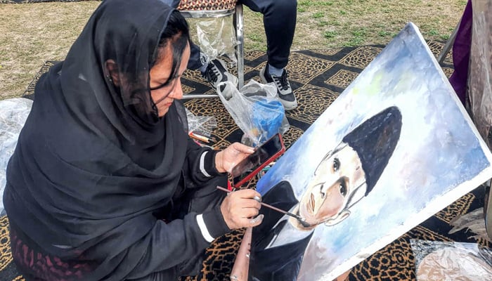 Participants giving final touches to the painting during the event in connection with the 147th birth anniversary of Quaid-e-Azam Muhammad Ali Jinnah on December 24, 2023. — AFP
