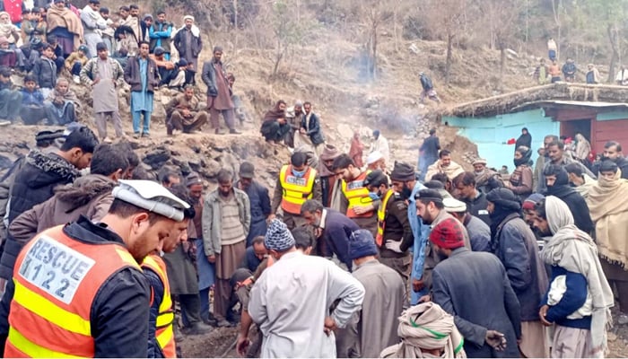 A large number of people and rescue workers gather at the site after a massive fire engulfed a house due to short-circuit in the Qalandarabad area in Abbottabad on December 24, 2023. — PPI