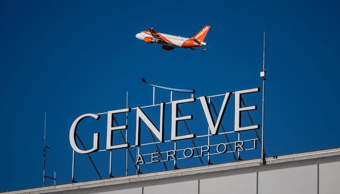 A commercial plane of low-cost airline EasyJet takes off behind a sign of Geneva International Airport in Geneva, on December 24, 2023. — AFP
