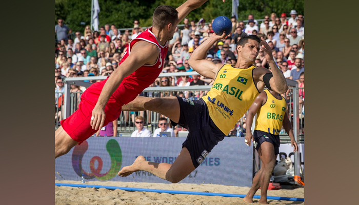 A representational image shows two people vying for a handball during a beach handball match. — Facebook/International Handball Federation - IHF