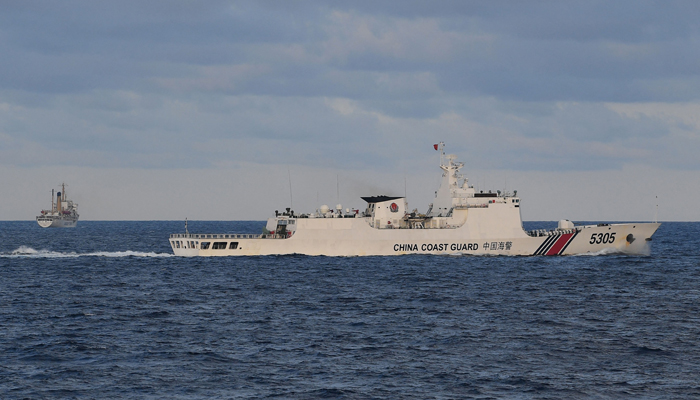 This photo taken on December 10, 2023 shows a Chinese coast guard ship shadowing a Philippine vessel (L) loaded with provisions for Filipino fishermen and troops in disputed waters of the South China Sea. — AFP