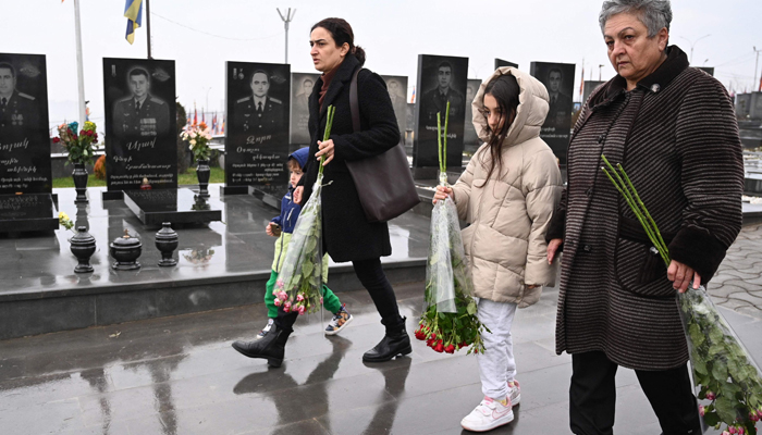 Refugees from Karabakh, carry flowers to lay on the grave of their husband and son, killed in the 2020 conflict with Azerbaijan, at the Yerablur Military Pantheon, a cemetery in the outskirts of Yerevan, on December 23, 2023. — AFP