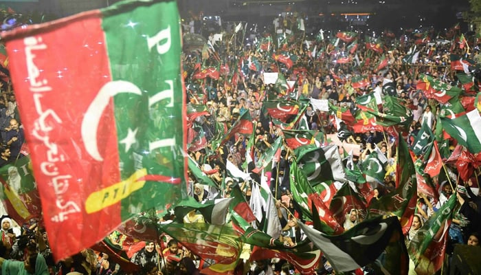 PTI supporters wave party flags as they take part in a rally in Karachi on April 10, 2022. — AFP