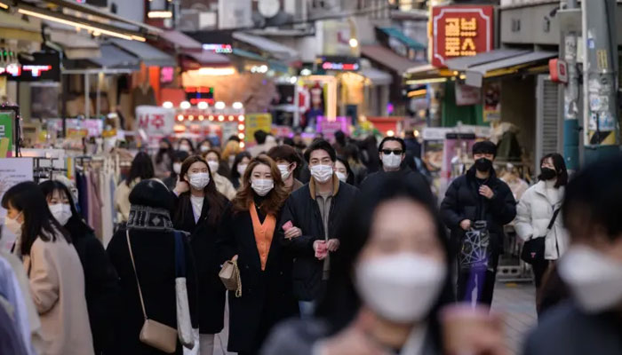 People walk along a commercial street in Seoul on February 24, 2021. — AFP