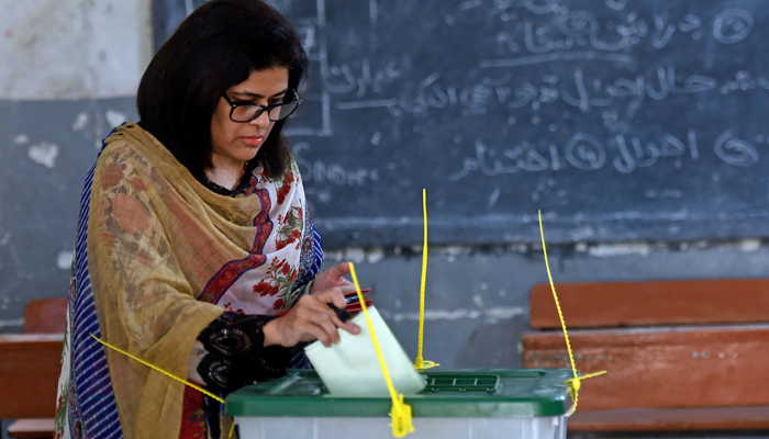A female voter casts her ballot at a polling station during the by-election for National Assembly seats, in Karachi on Sunday. — AFP
