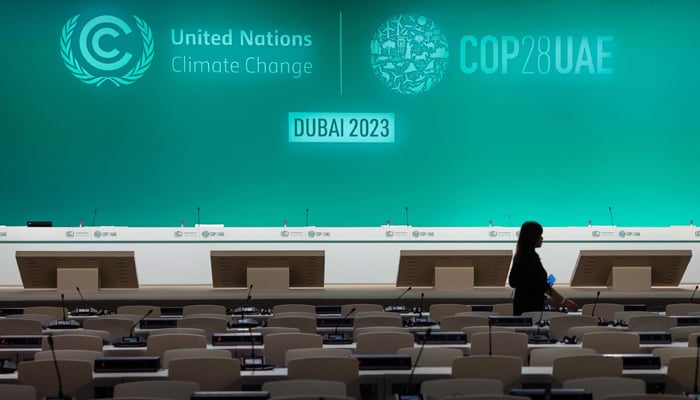 A woman walks in an empty conference room ahead of the COP28 United Nations climate summit in Dubai, UAE, on November 28, 2023. — AFP