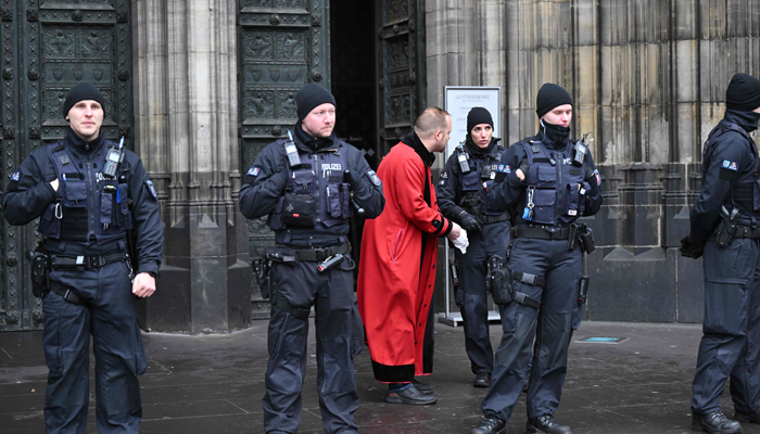 A sidesman of the Cathedral talks to a policewoman in front of the Cologne Cathedral on December 24, 2023. — AFP