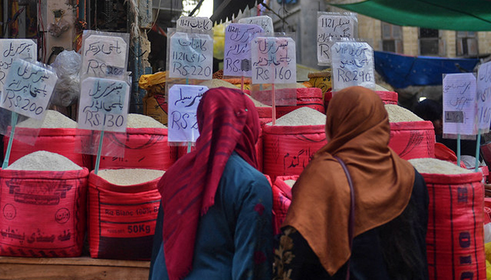 Women check rice prices at a main wholesale market. — AFP/File