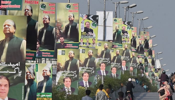 Commuters ride past the welcoming posters of former PM Nawaz Sharif in Rawalpindi, on October 13, 2023. — AFP