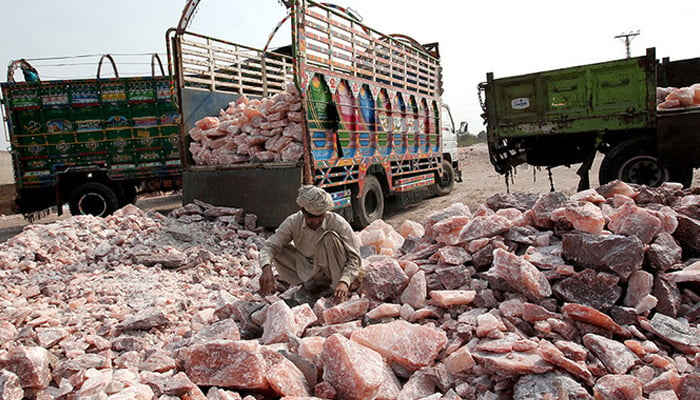 A Pakistani worker collects salt stones to be loaded onto a truck outside the Khewra salt mine.—AFP/File