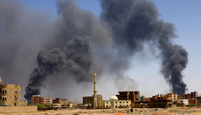 A man walks while smoke rises above buildings after aerial bombardment, during clashes between the paramilitary RSF and the army in Khartoum North, Sudan. — AFP/File
