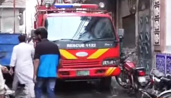 A Rescue 1122 vehicle stands outside the affected building as the cooling process continues as seen in this still taken from a video. — YouTube/Geo News