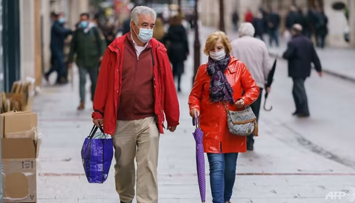 People wearing face masks walk in Burgos, northern Spain. — AFP/File