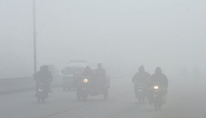 Motorists make their way along a street amid heavy fog on Thursday.—AFP