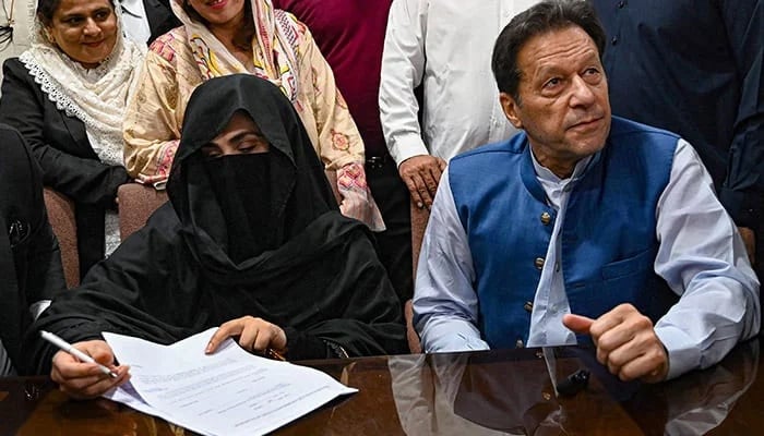 Former prime minister Imran Khan (right) along with his wife Bushra Bibi (center) signs surety bonds for bail in various cases, at the registrars office in the Lahore High Court on July 17, 2023. — AFP