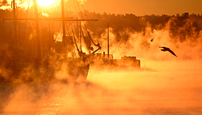 Vapor rises from the water around a historic tri-master charter sailing ship moored in a port of Oslo on January 5, 2024, as the morning sun paints the scene in golden light during unusually cold temperatures of around -22 degrees Celsius in the Norwegian capital. — AFP