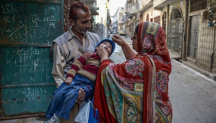 A health worker (R) administers the polio vaccine to a child during a vaccination campaign in Rawalpindi, Pakistan. — AFP/File