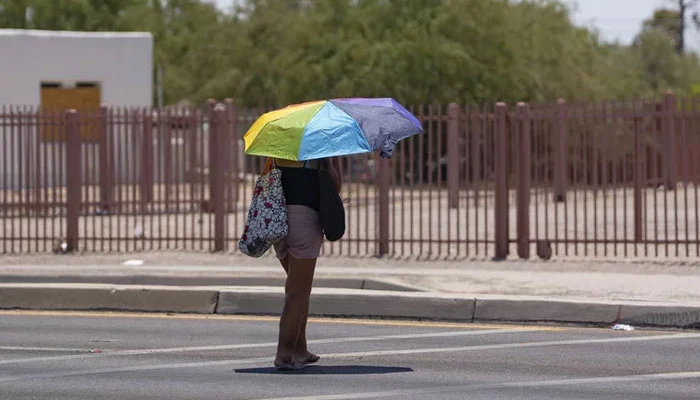 A woman shields herself from the sun with an umbrella during a heatwave in Tucson, Arizona, on July 15, 2023. — AFP