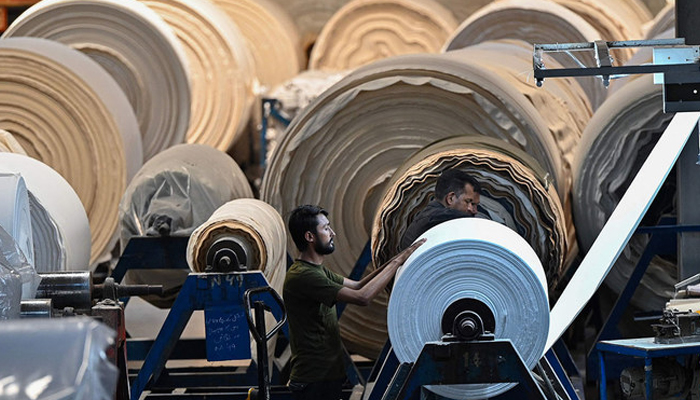In this picture, a worker operates a machine preparing fabric at the Kohinoor Textile Mills in Lahore on July 20, 2023. — AFP
