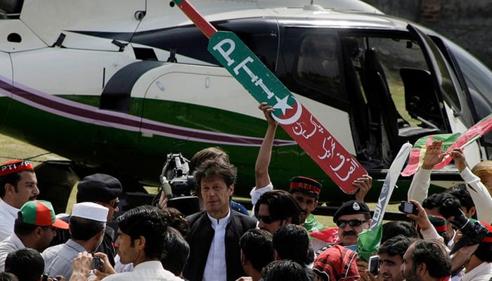 Behind the Former PTI chairman Imran Khan (C) a worker holds the symbol of PTI. — AFP/File