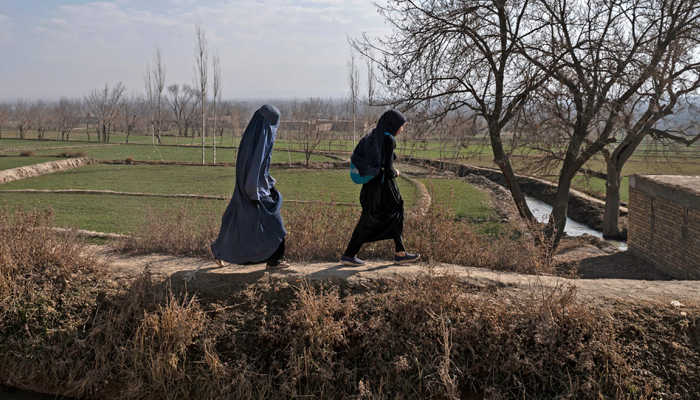 Afghan women walk along a path at Nawabad Kako Sahib area in Baraki Barak district of Logar Province on January 7, 2024. — AFP
