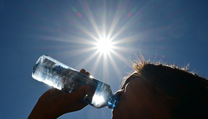 A child sips water from a bottle under a scorching sun on August 30, 2022, in Los Angeles, California. — AFP