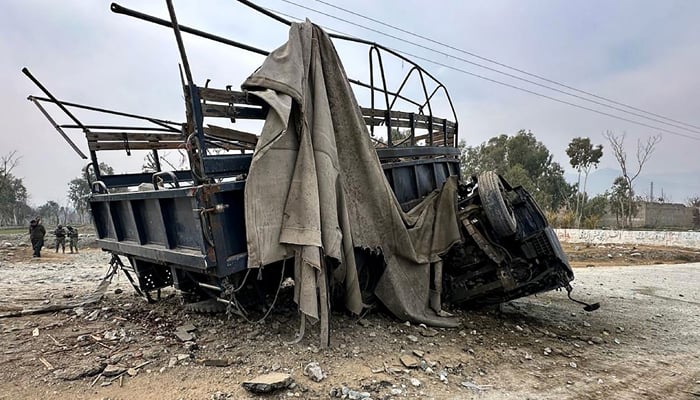Paramilitary soldiers stand guard in front of the wreckage of a police truck at the site of a roadside bomb blast in Bajaur district, around 14 kms from the border with Afghanistan on January 8, 2024. — AFP