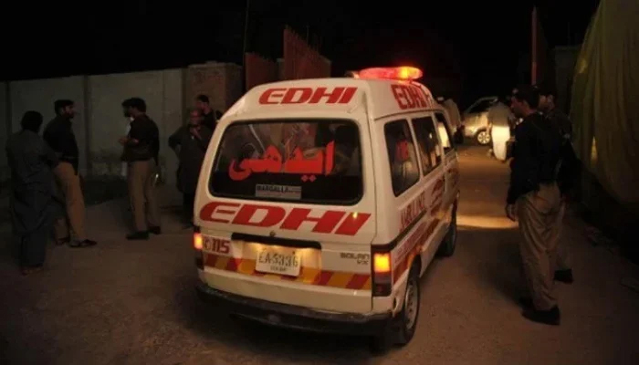 This image shows an Edhi ambulance passing by police officials.—AFP/File