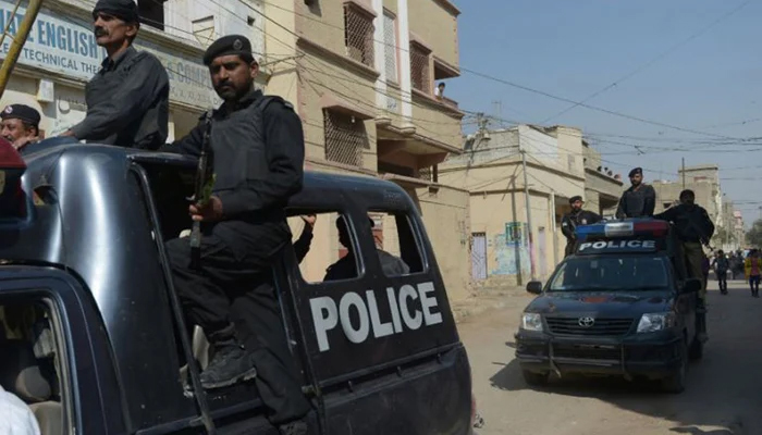 Sindh Police personnel can be seen passing on a police vehicle in Karachi.—AFP/File