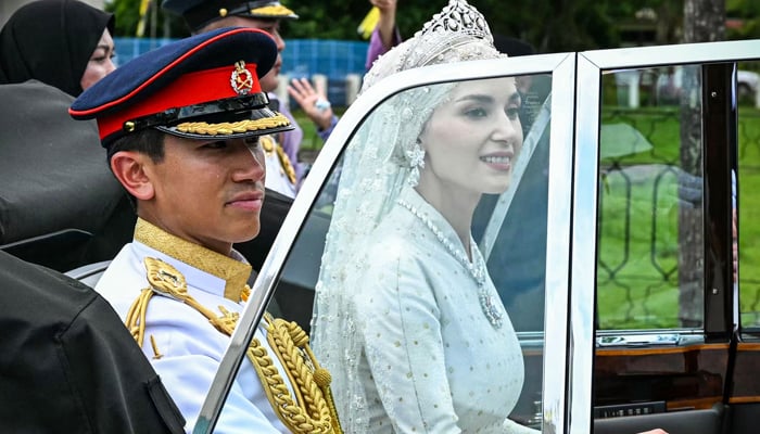 Prince Abdul Mateen (L) and Yang Mulia Anisha Rosnah are seen in their car during their wedding procession in Bruneis capital Bandar Seri Begawan on January 14, 2024. — AFP