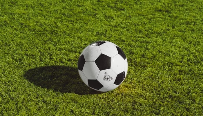 This representational image shows a football on a field. — Unsplash