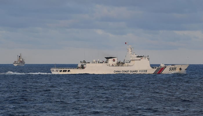 This photo taken on December 10, 2023 shows a Chinese coast guard ship shadowing a Philippine vessel (L) loaded with provisions for Filipino fishermen and troops in disputed waters of the South China Sea. — AFP
