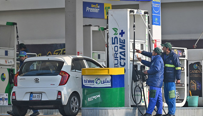 Employees at a fuel station in Islamabad attend to their customers. — AFP/File