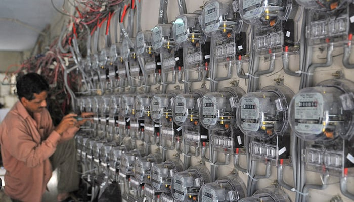 A technician fixes new electricity meters at a residential building in Karachi, Pakistan. — AFP/File