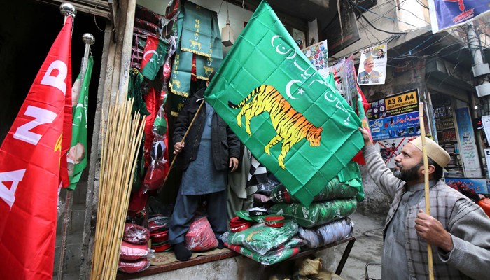 A man is buying a political party flag from the shop at Qissa-Khwani Bazaar for the upcoming General Election on January 15, 2024. — INP