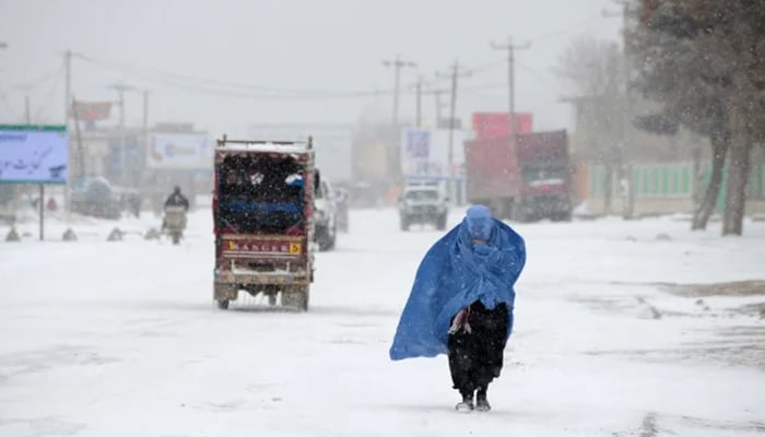 An Afghan woman makes her way as snow falls in the city of Mazar-i-Sharif. — AFP/File