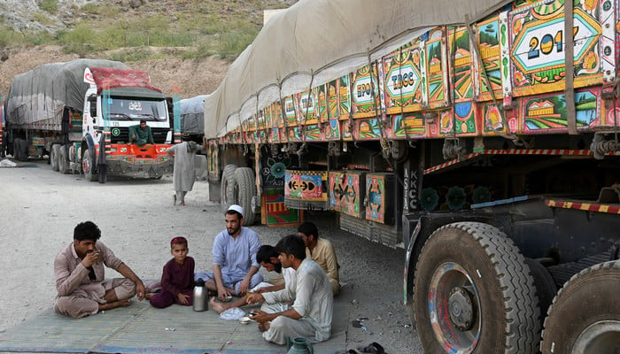 Drivers along with a boy drink tea next to trucks parked along a road near the Pakistan-Afghanistan border in Torkham. — AFP/File