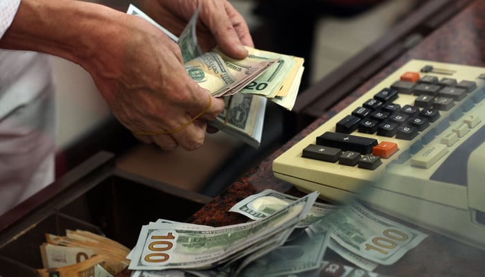 A teller counts US dollar bills at an exchange office in Ankara on July 20, 2023. — AFP
