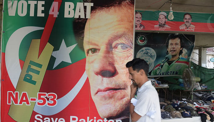 A man walks past a poster of Imran Khan, founding head of the PTI at a market in Islamabad. — AFP/File