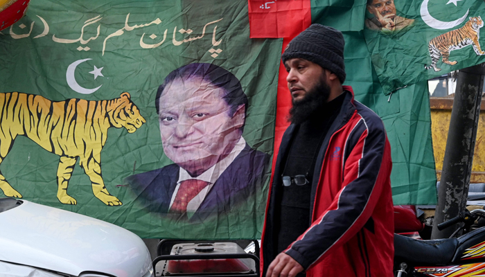 A man walks past the banners of the Pakistan Muslim League (PML) party featuring its leader Nawaz Sharif, along a street in Lahore on January 16, 2024, ahead of the upcoming general elections. — AFP