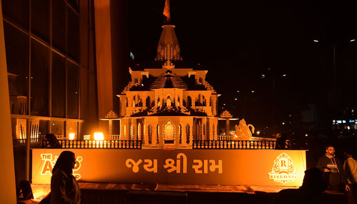 People stand near a wooden replica of the Ayodhya Ram temple, in Ahmedabad on January 19, 2024. — AFP