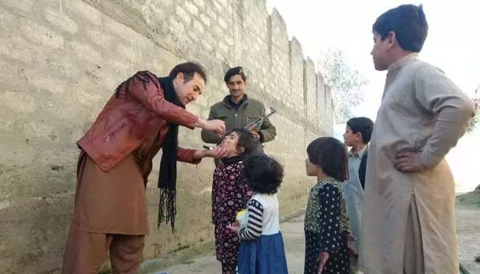 A polio worker administers the oral polio vaccine to a child under strict security in Sadiq Abad village of Bajaur District on February 17. —Pakistan Forward/Hanif Ullah