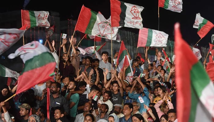 Supporters of Pakistani political Muttahida Qaumi Movement (MQM) party hold party flags. — AFP/File