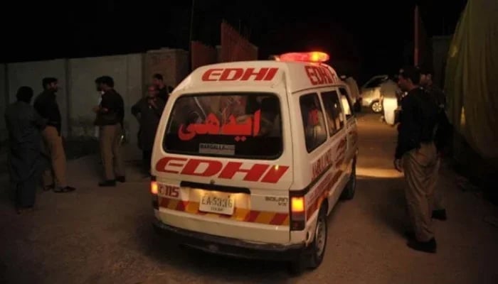 This image shows an Edhi ambulance passing by police officials. —AFP/File