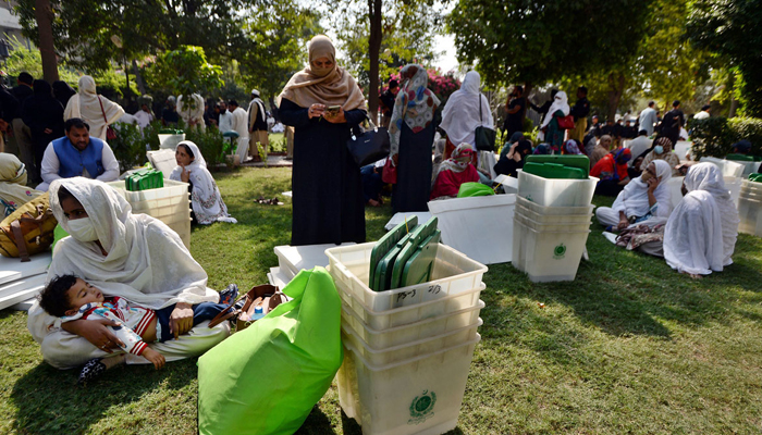 Polling staffers waiting for transports after receiving ballot boxes and election materials for their polling station at Nishter Hall on October 15, 2022. — APP