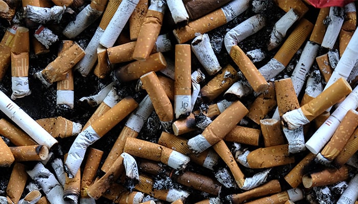 An ashtray filled with cigarette butts is seen on an outdoor smoking stand at a bus stop. — AFP/File