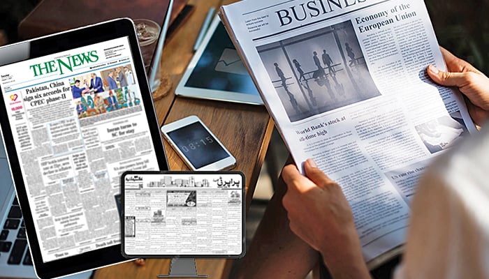 A person reads a newspaper, whereas the tablets show The News e-paper editions open on the screen.  Jang Media Group