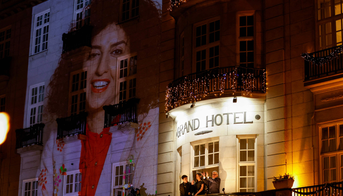Kiana Rahmani (C) and Ali Rahmani (L), children of Narges and her husband Taghi Rahmani, wave from the balcony during a torchlight procession organised by The Norwegian Peace Council for the winner of the Nobel Peace Prize, Narges Mohammadi, at the Grand Hotel in central Oslo on December 10, 2023. — AFP